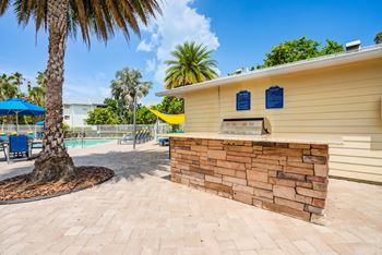 A yellow building with a stone wall and a palm tree in front